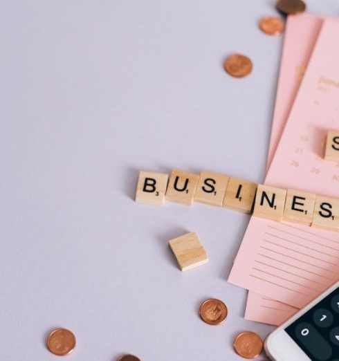 Startup Costs - Flat lay of a small business planning scene with coins, smartphone calculator, and letter tiles.