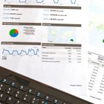 Credit Report - Flatlay of a business analytics report, keyboard, pen, and smartphone on a wooden desk.