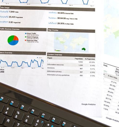 Credit Report - Flatlay of a business analytics report, keyboard, pen, and smartphone on a wooden desk.