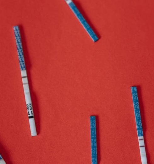 Health Checks - Multiple pregnancy test strips scattered on a vibrant red backdrop, symbolizing fertility and anticipation.