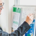 Loans - Businessman in suit writes on whiteboard displaying mortgage loan rates during a real estate meeting.