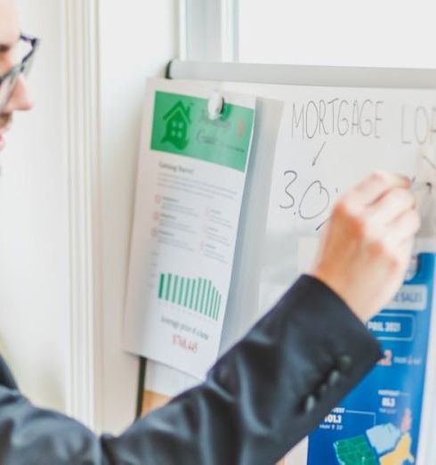 Loans - Businessman in suit writes on whiteboard displaying mortgage loan rates during a real estate meeting.