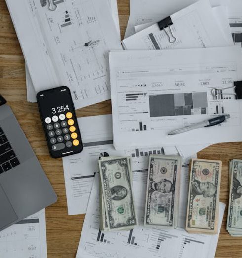 Gross Revenue - Overhead view of financial documents, cash, and technology on a wooden desk.