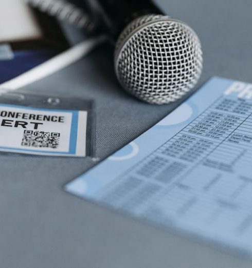 Brand Voice - Close-up of a microphone, name tag, and program guide on a table at a business conference.