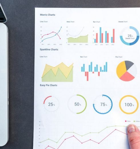 Data Analytics - Detailed charts and graphs on a document next to a laptop, representing data analysis.