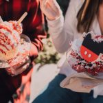 User-Generated Content - Two people enjoying vibrant ice cream sundaes outdoors on a sunny day.