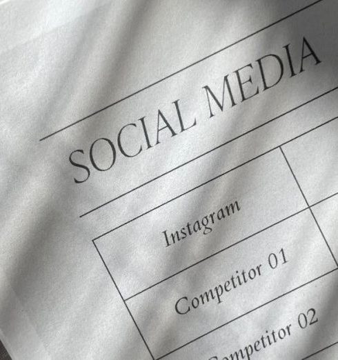 Competitor Analysis - Closeup of a social media plan on paper with fabric texture and dramatic shadows.