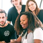 Marketing Strategy - A diverse group of young professionals collaborating around a laptop in a modern office setting. Perfect for business or tech concepts.