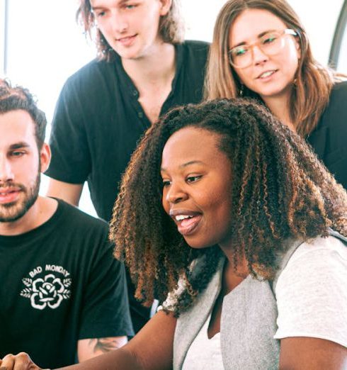 Marketing Strategy - A diverse group of young professionals collaborating around a laptop in a modern office setting. Perfect for business or tech concepts.