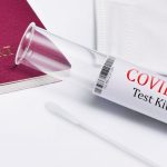 A/B Testing - Close-up of COVID-19 test kit with a passport, symbolizing travel safety during the pandemic.