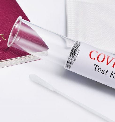 A/B Testing - Close-up of COVID-19 test kit with a passport, symbolizing travel safety during the pandemic.