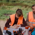 Seasonal Campaign - Volunteers in safety vests prepare for a search mission at a park near a water body.