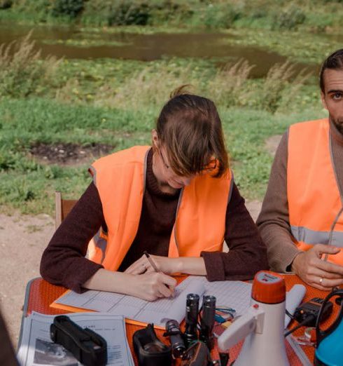 Seasonal Campaign - Volunteers in safety vests prepare for a search mission at a park near a water body.