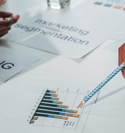 Data-Driven Marketing - Team working on marketing strategy using data charts and papers in an office meeting.