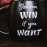 Motivation - Black mug with inspirational quote 'You can win if you want' reflected on a dark surface, creating a motivational ambiance.