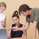 Feedback - Group of professionals collaborating on a project, discussing ideas around a laptop.