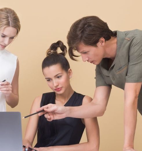 Feedback - Group of professionals collaborating on a project, discussing ideas around a laptop.