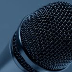 Public Speaking - A detailed close-up of a microphone with a blue monochrome background, highlighting its intricate mesh design.