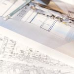 Development Plan - Close-up of architectural blueprints and 3D design on paper with pencil on a desk.