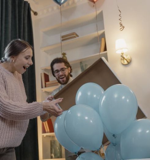 Expectations - Friends joyfully celebrate a gender reveal with blue balloons indoors.