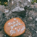 Empathy - Stay Safe Be Kind text carved on stone in green park during coronavirus pandemic