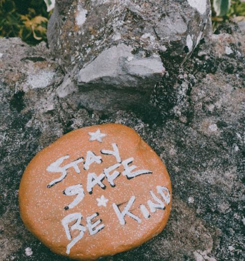 Empathy - Stay Safe Be Kind text carved on stone in green park during coronavirus pandemic