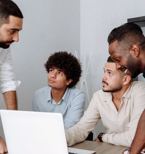 Partnerships - Diverse group of business professionals engaging in a collaborative meeting around a laptop.