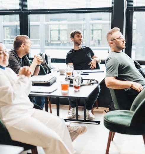 Product Diversification - Modern office setting with diverse team in discussion, seated around a table by large windows.