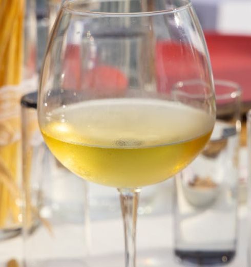 Upselling - Elegant wine glass with white wine amidst table setting at an outdoor dining area.