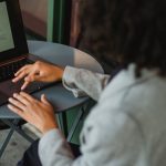 Sales Funnel - A woman working remotely on a laptop at an outdoor café table, focusing on a sales funnel diagram.