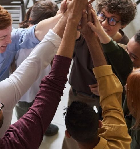 Company Culture - A diverse group of professionals high-fiving in a modern office, showcasing teamwork and collaboration.