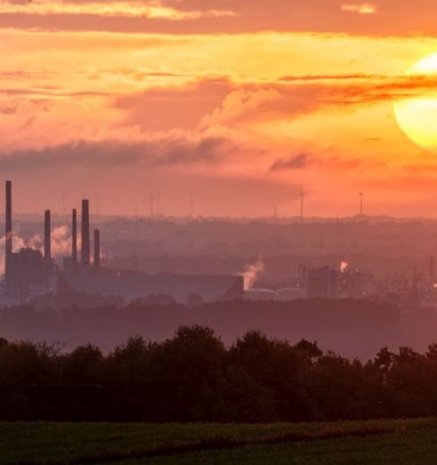 Expansion Timing - A stunning sunset over an industrial landscape with smoke rising from factory chimneys.