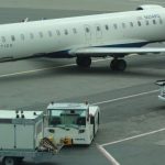 Operational Efficiency - Delta Connection airplane on airport tarmac with service vehicles preparing for takeoff.