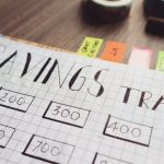 Financial Planning - Close-up of a handmade savings tracker with colored tabs on a wooden table, ideal for financial planning visuals.