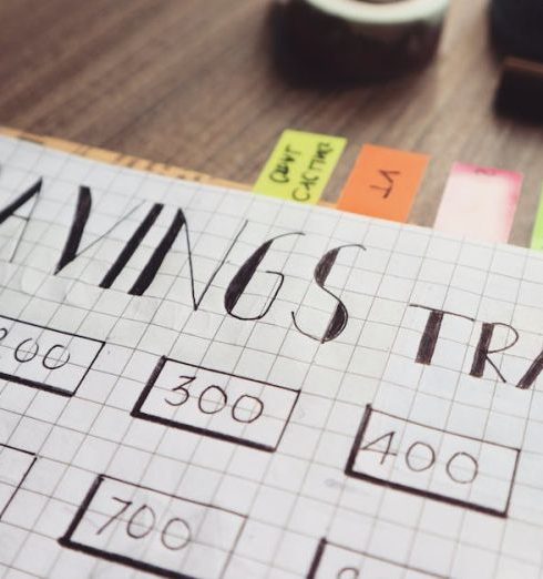 Financial Planning - Close-up of a handmade savings tracker with colored tabs on a wooden table, ideal for financial planning visuals.