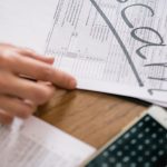 Complaints - Close-up of hands examining documents marked 'scam' with a calculator nearby.