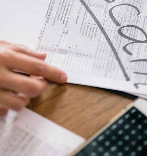 Complaints - Close-up of hands examining documents marked 'scam' with a calculator nearby.