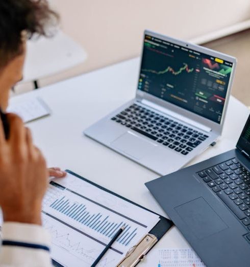 CRM Tools - Man analyzing stock market charts on laptops while talking on a cellphone.