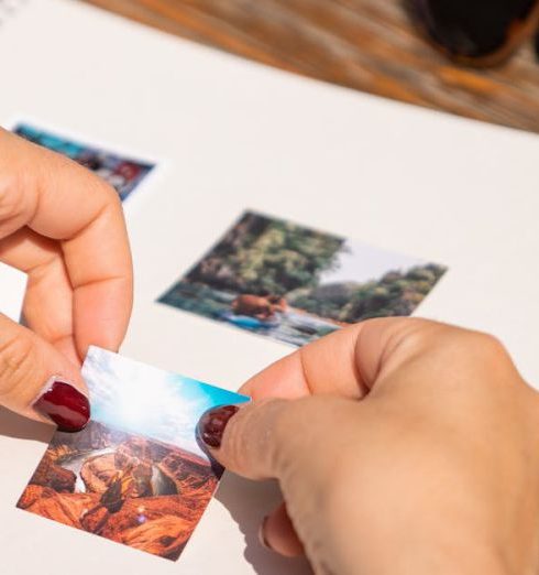 Personalization - Hands arranging photos in a scrapbook under sunlight, capturing summer memories.