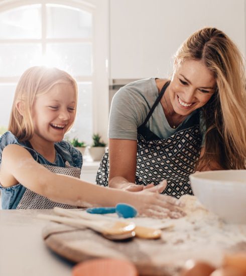 Happy young girl with her mother making dough